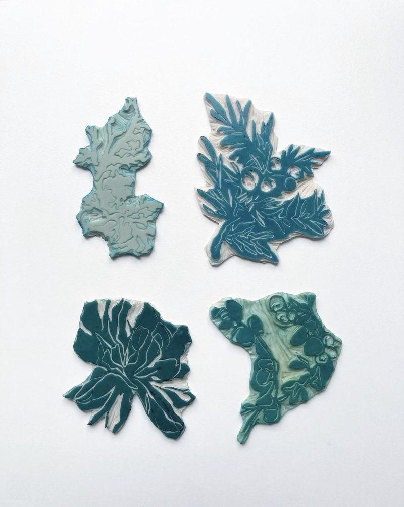 Four small carved and inked lino blocks in blue-green tones